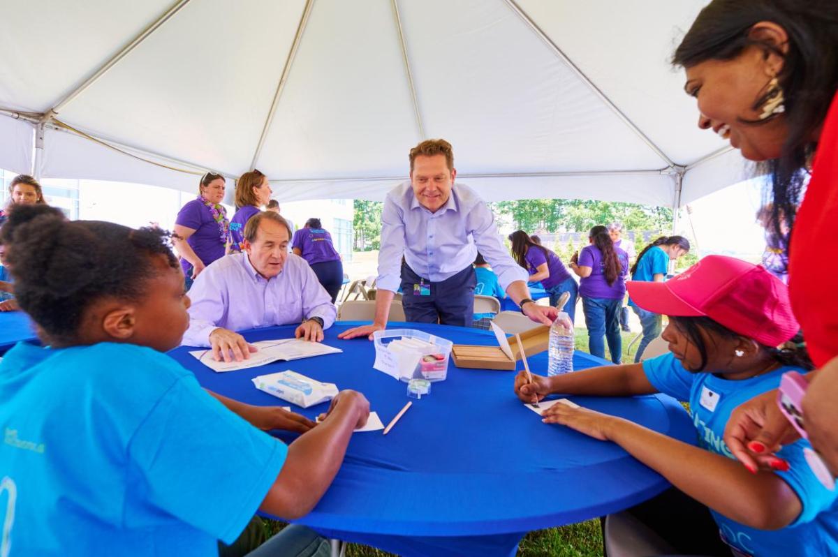 CEO stands over table teaching students