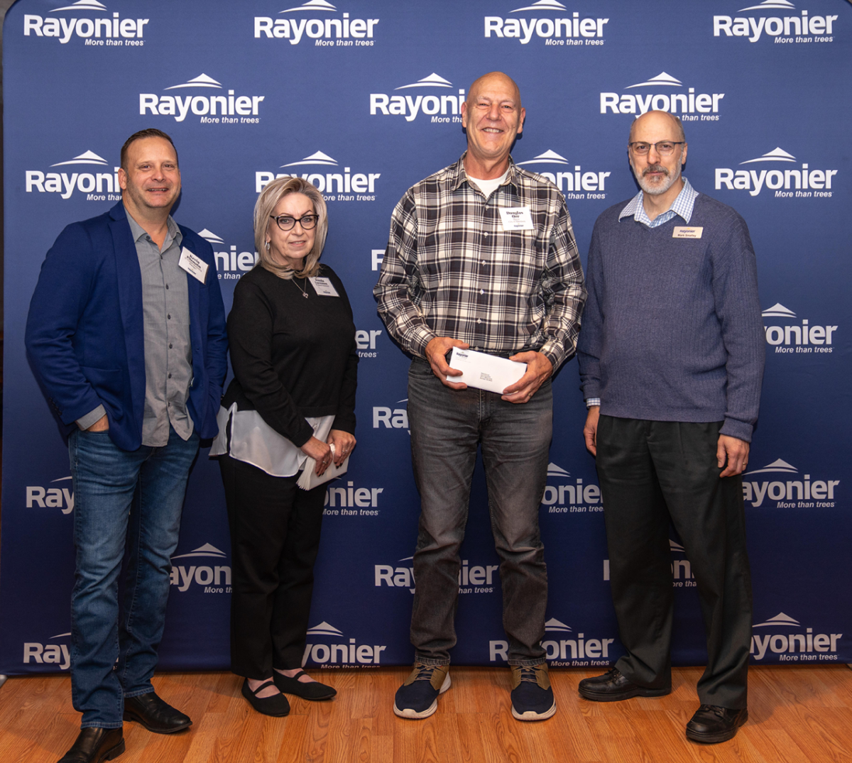 Four people standing together, one holding a check