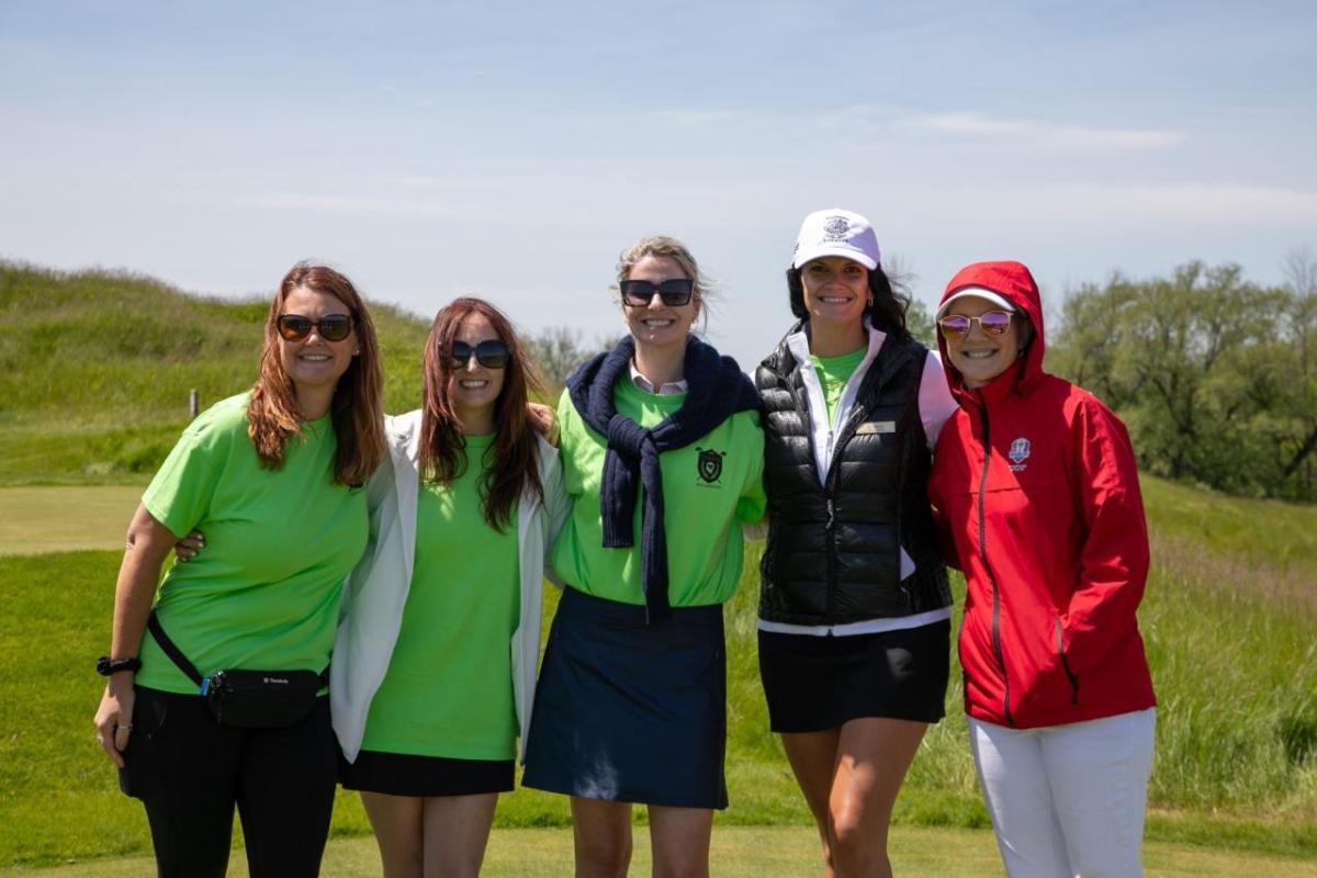 Four people in bright green and one in red standing together outside