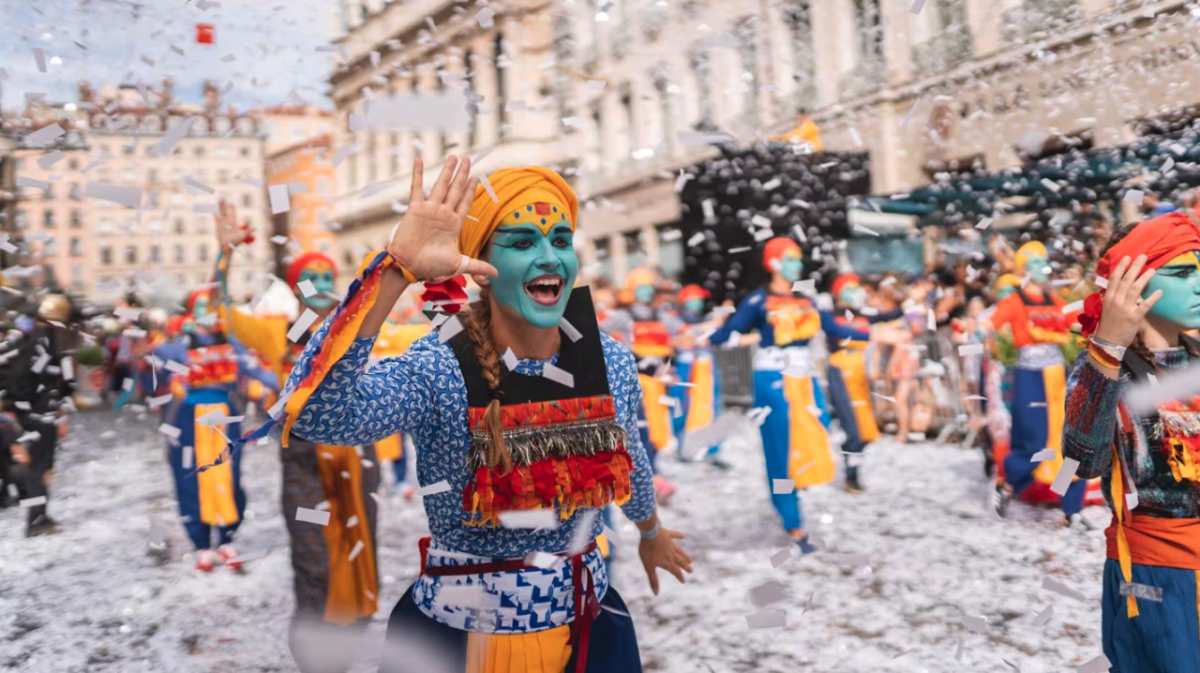 A person with a bright clothes and a brightly painted face amongst others in an event