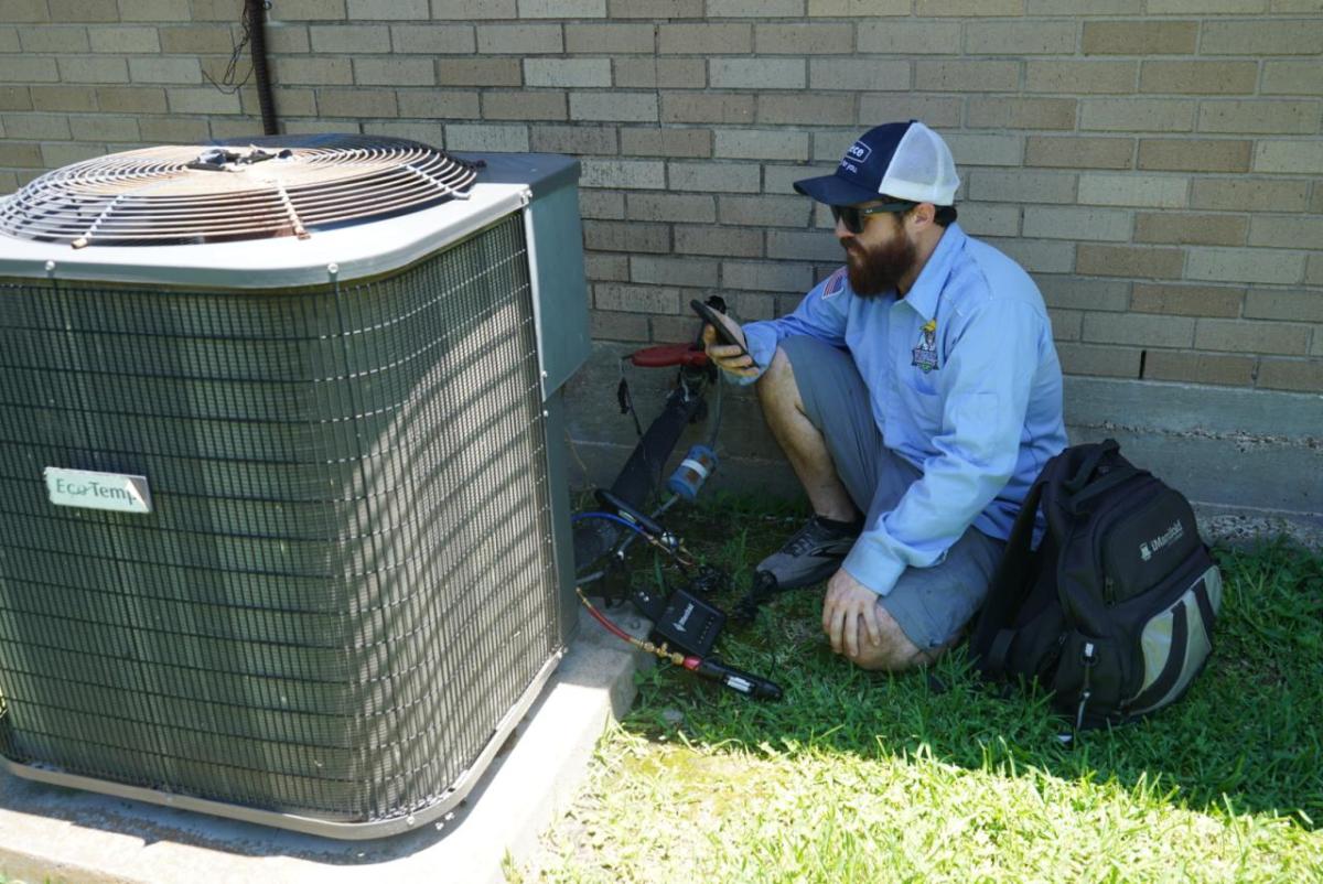 A worker next to an outdoor HVAC unit