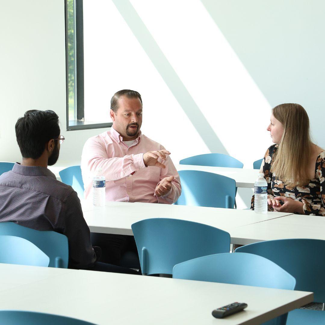 Three people sat at a table having a discussion