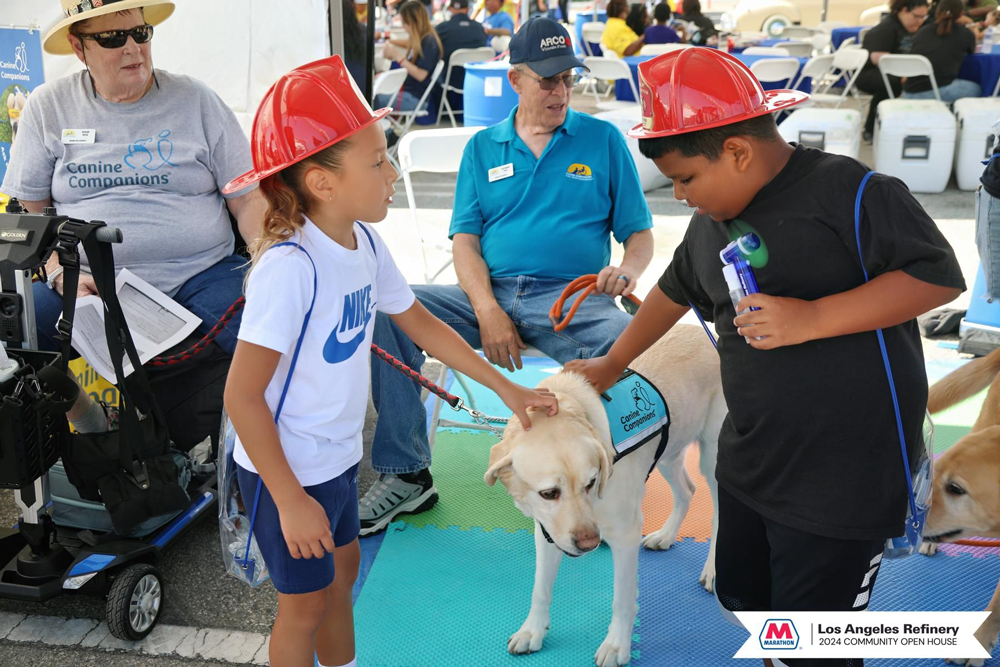 Kids in fire helmets petting a yellow lab