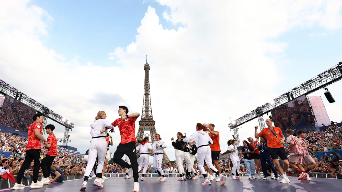 People on a stage dancing with the Eiffel Tower behind them