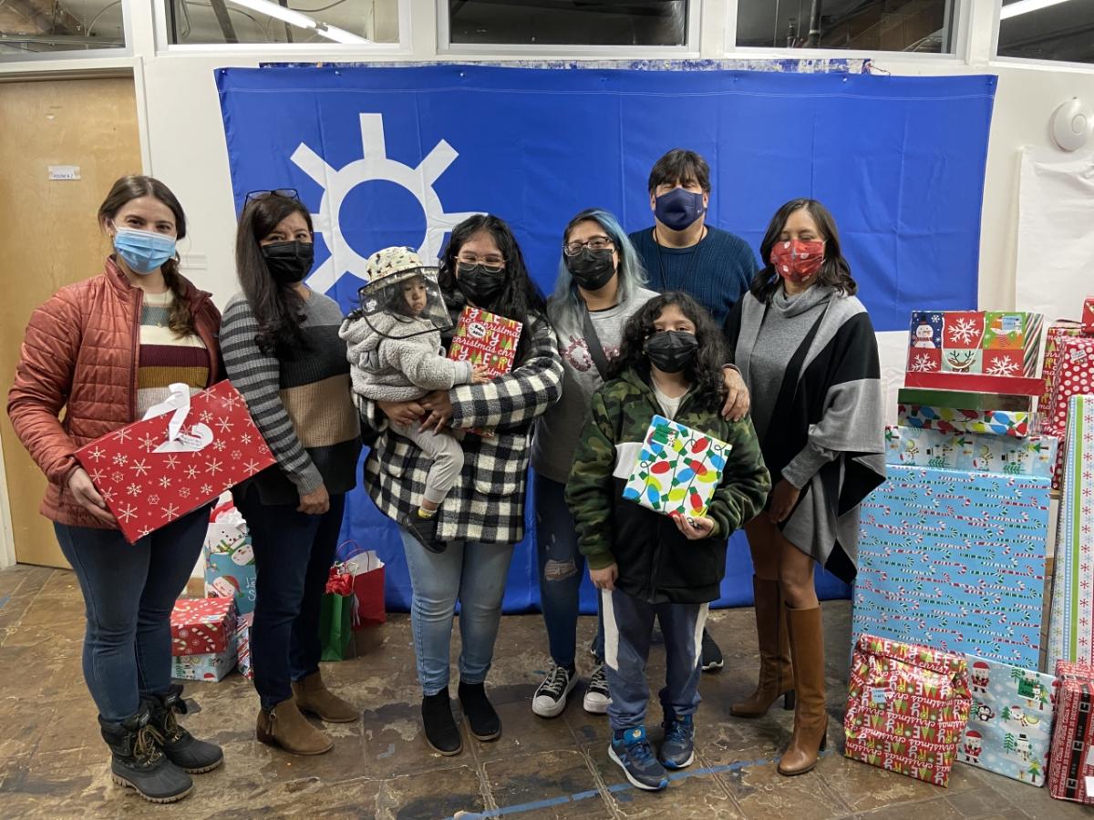 AEG employees surround a family at CARACEN in Los Angeles with presents for the holidays.