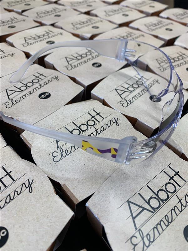 Scientist glasses with MilliporeSigma logo rests on top of small planters that say, "Abbott Elementary"