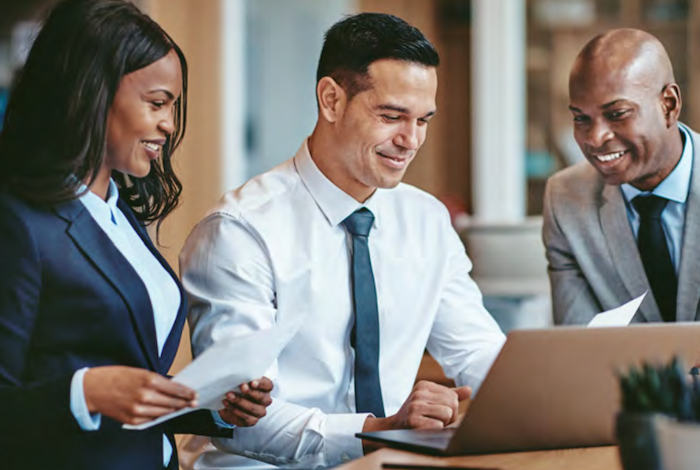 Three people at work viewing a laptop.