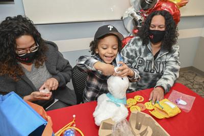 Child seated with two adults receives an Aflac My Special Duck.