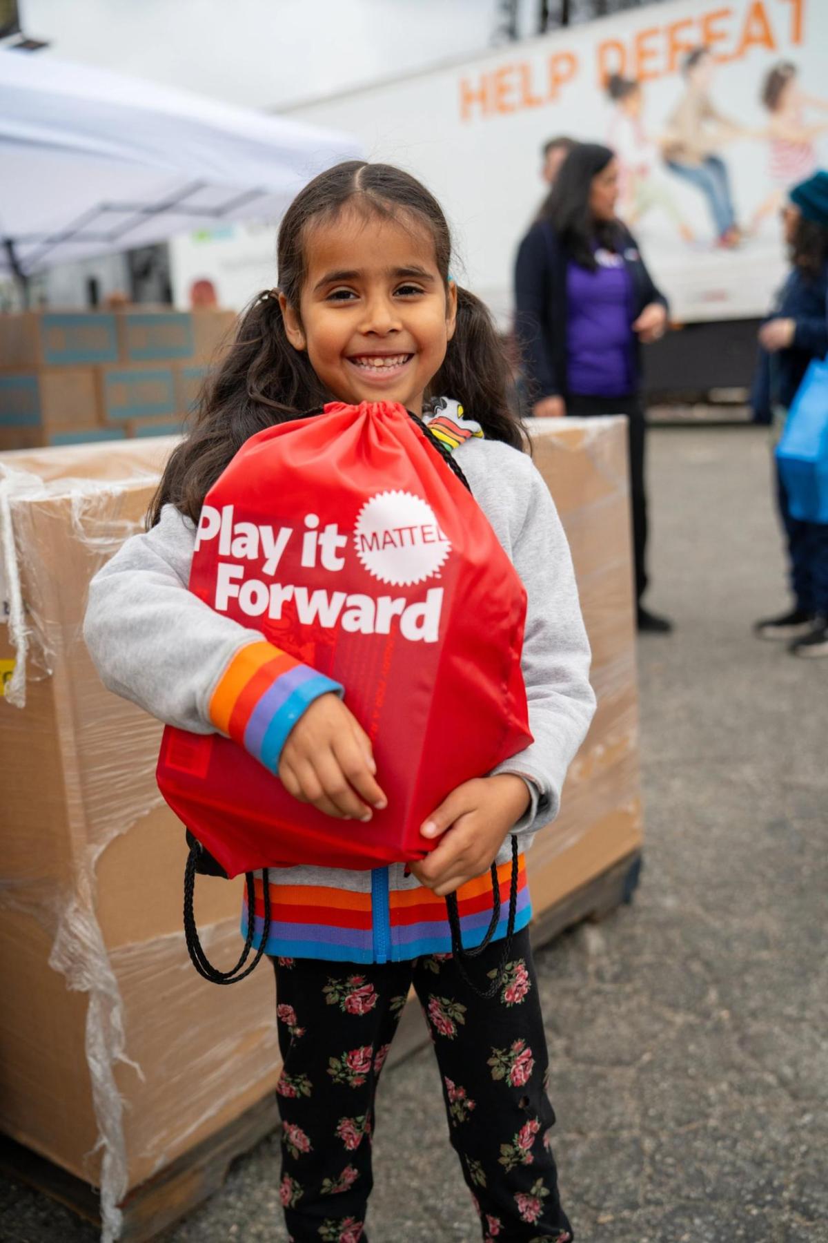 Child holding a Mattel Play it Forward bag