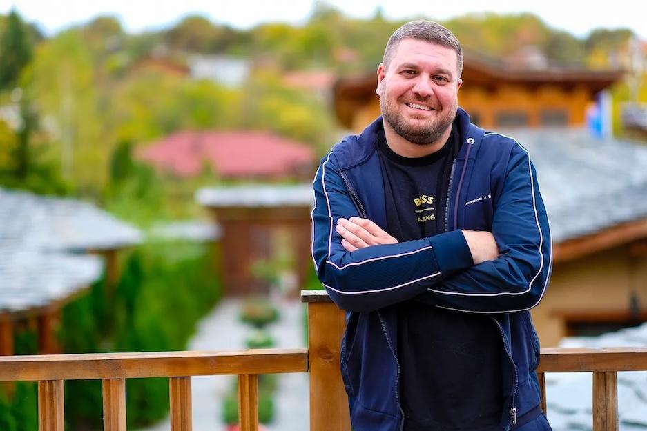 Alexander Ivanov leading up against a railing and smiling.