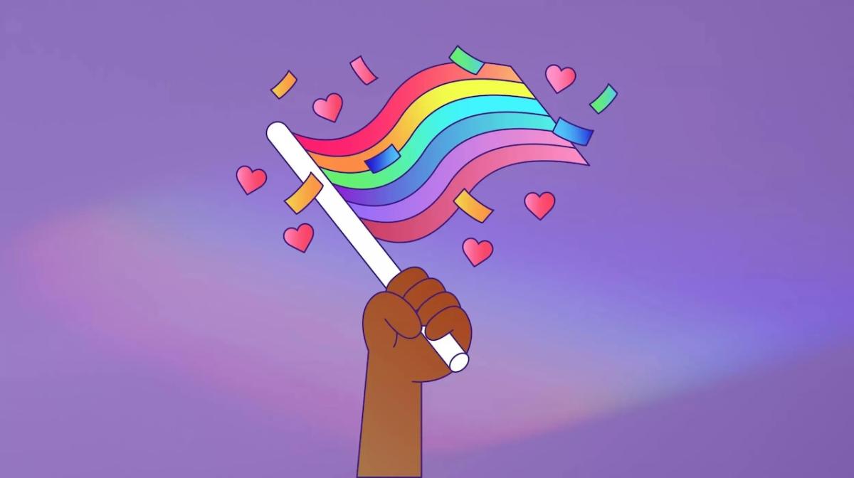 All about Pride. A hand is shown holding a Pride rainbow flag.