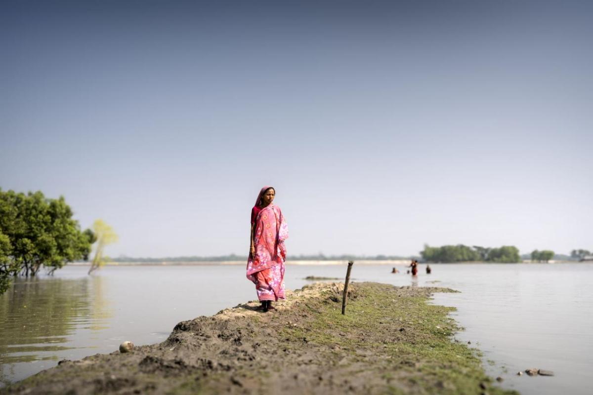 A woman walks along a flooded field. 