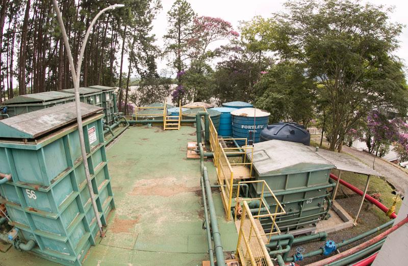 outdoor enclosed tanks and piping on a rooftop, trees in the background