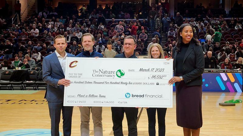 five people standing with large check 