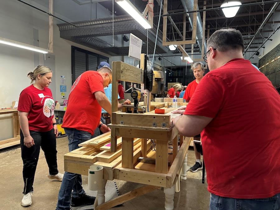 KeyBank volunteers cutting and glueing sections of bedframes.