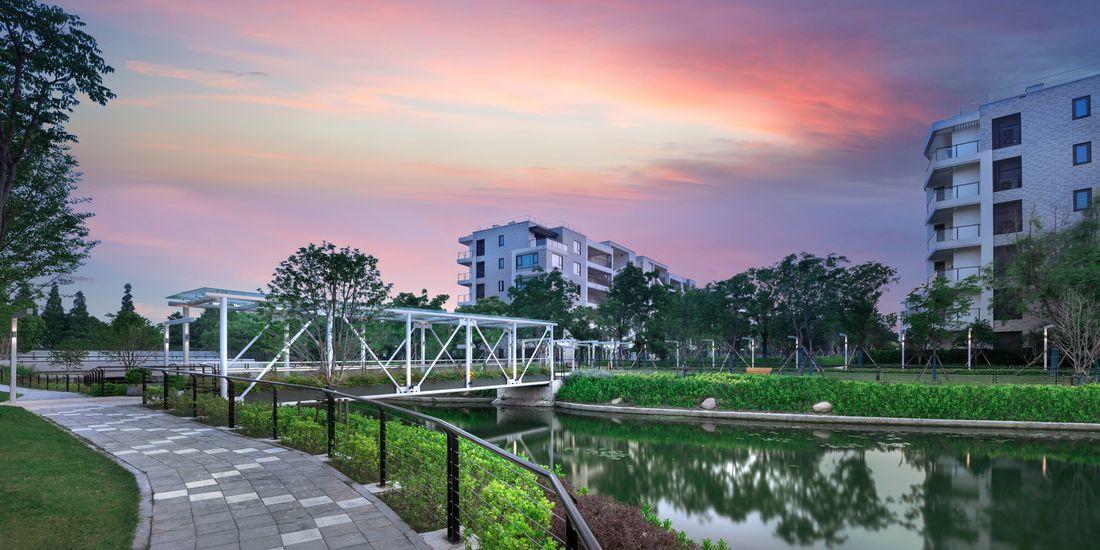 Bridge over water set before apartments at sunset