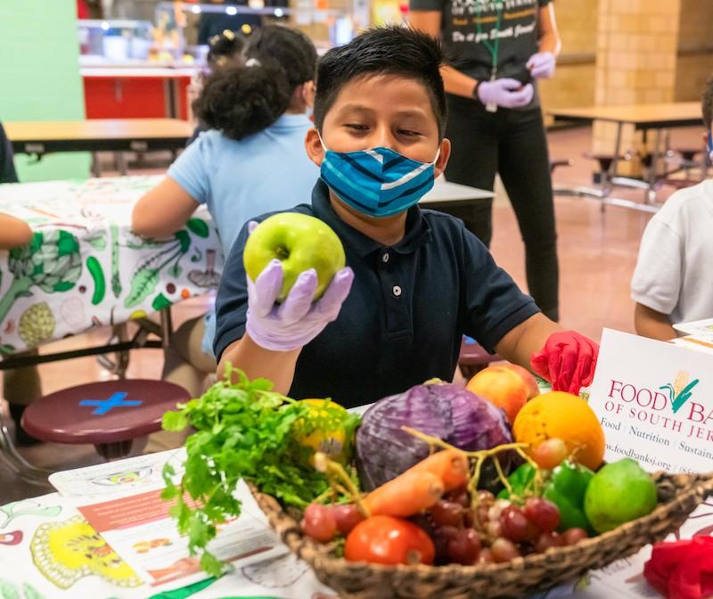 Young boy in a mask holding an apple.