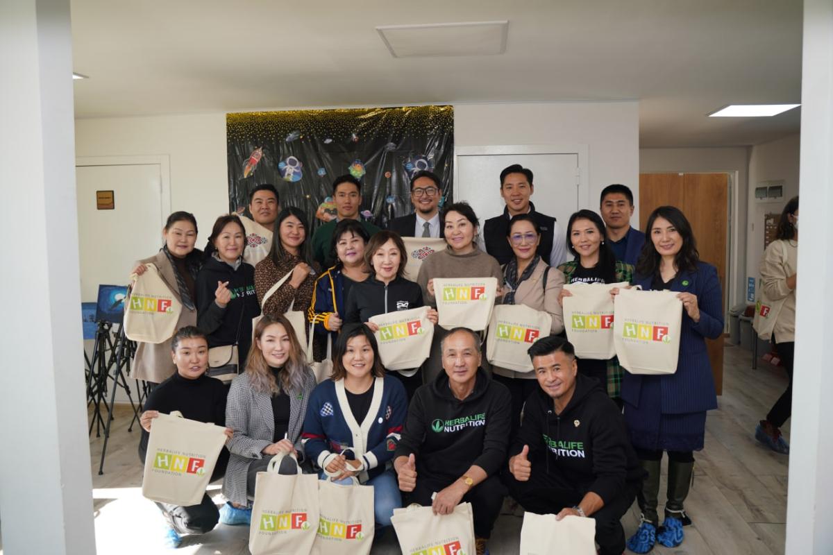 Group of people holding Herbalife Nutrition Foundation tote bags