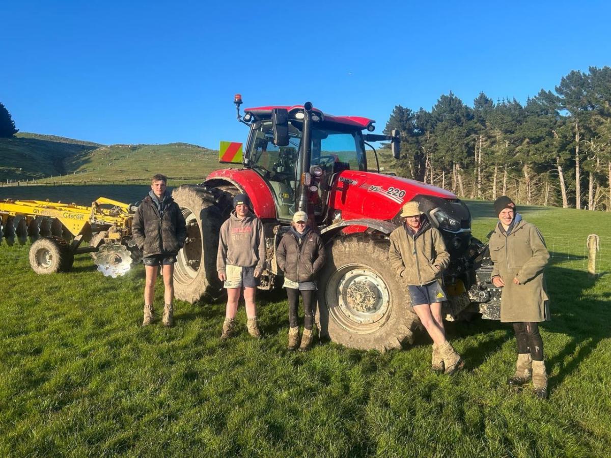 Five people stood in front of a red tractor