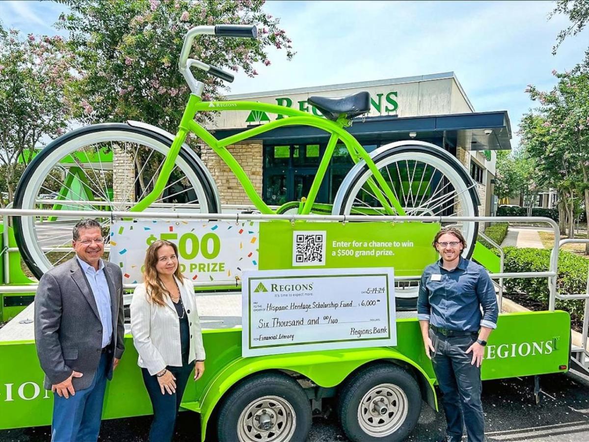 People stood in front of a large green bike on an event float with a cheque on the front 