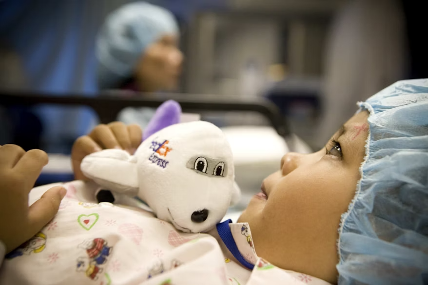 Child in hospital bed with stuffed FedEx plane