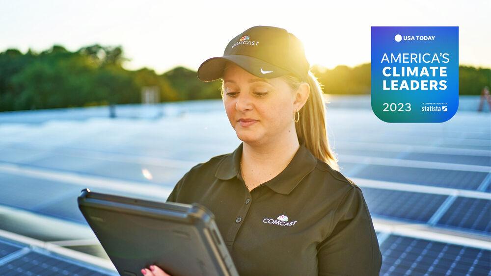 Comcast employee stood in a solar farm holding a tablet PC