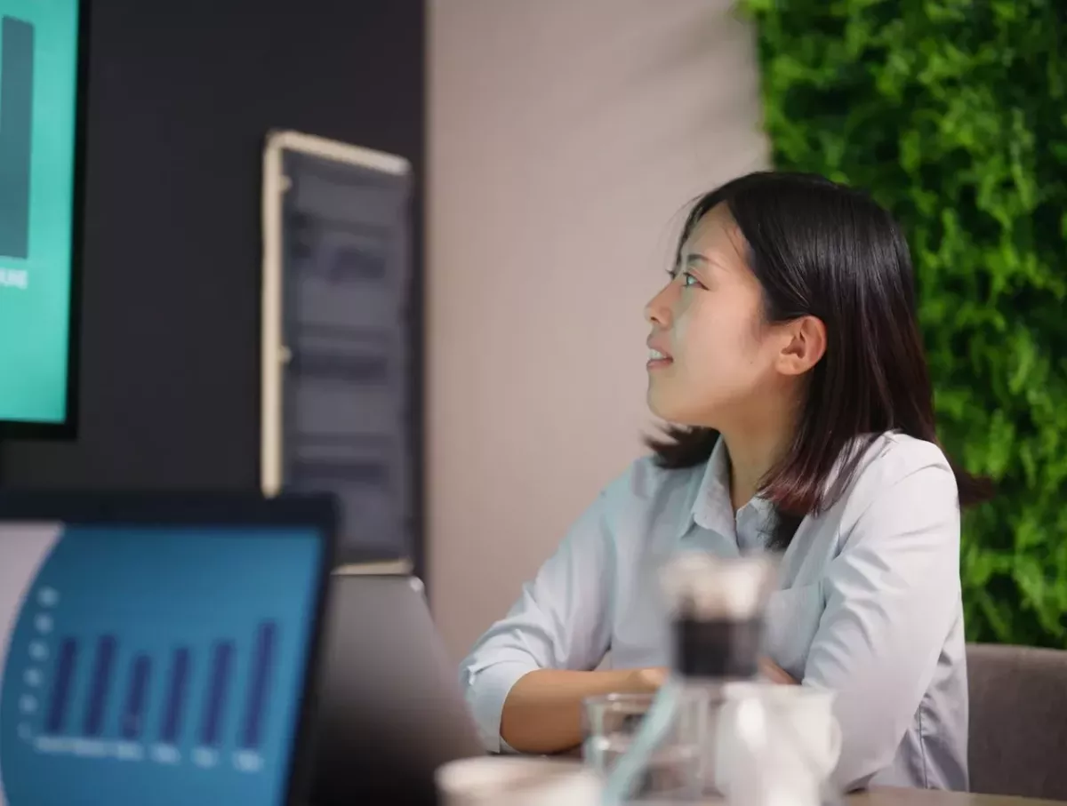 A person sat at a table looking towards a screen on the wall