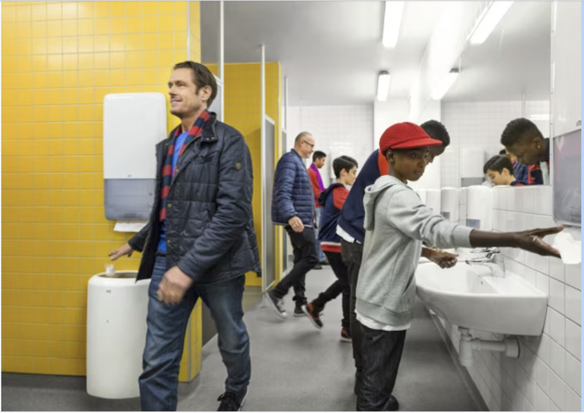 People in a public bathroom using Tork's new hygiene products to wash their hands