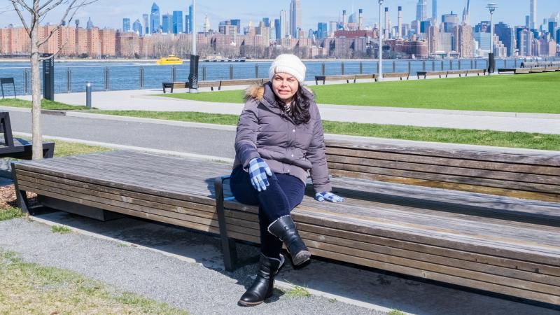 Cristina Herrera sitting on a park bench, a river in the background