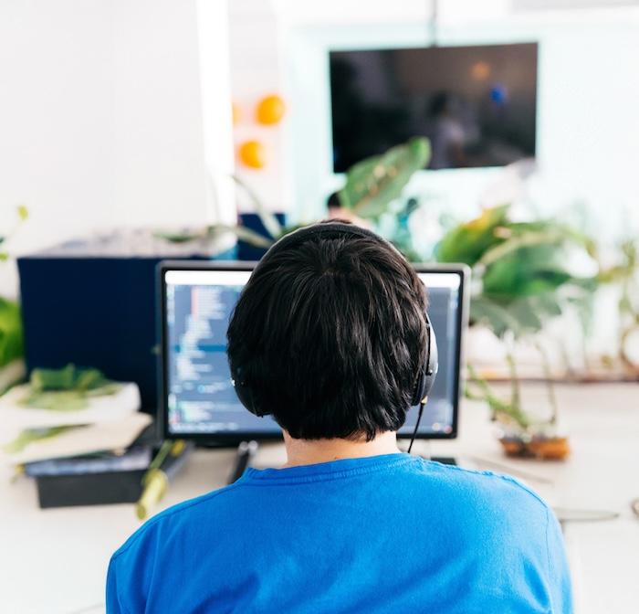 Operator seated behind a desktop computer wearing headphones.