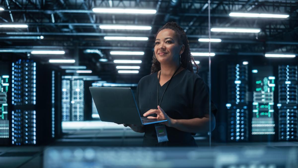 Female holding a laptop in a server room.