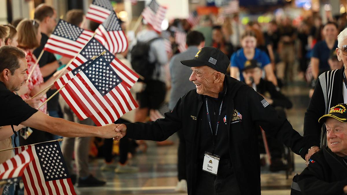 People waving American flags and shaking hands with war veterans