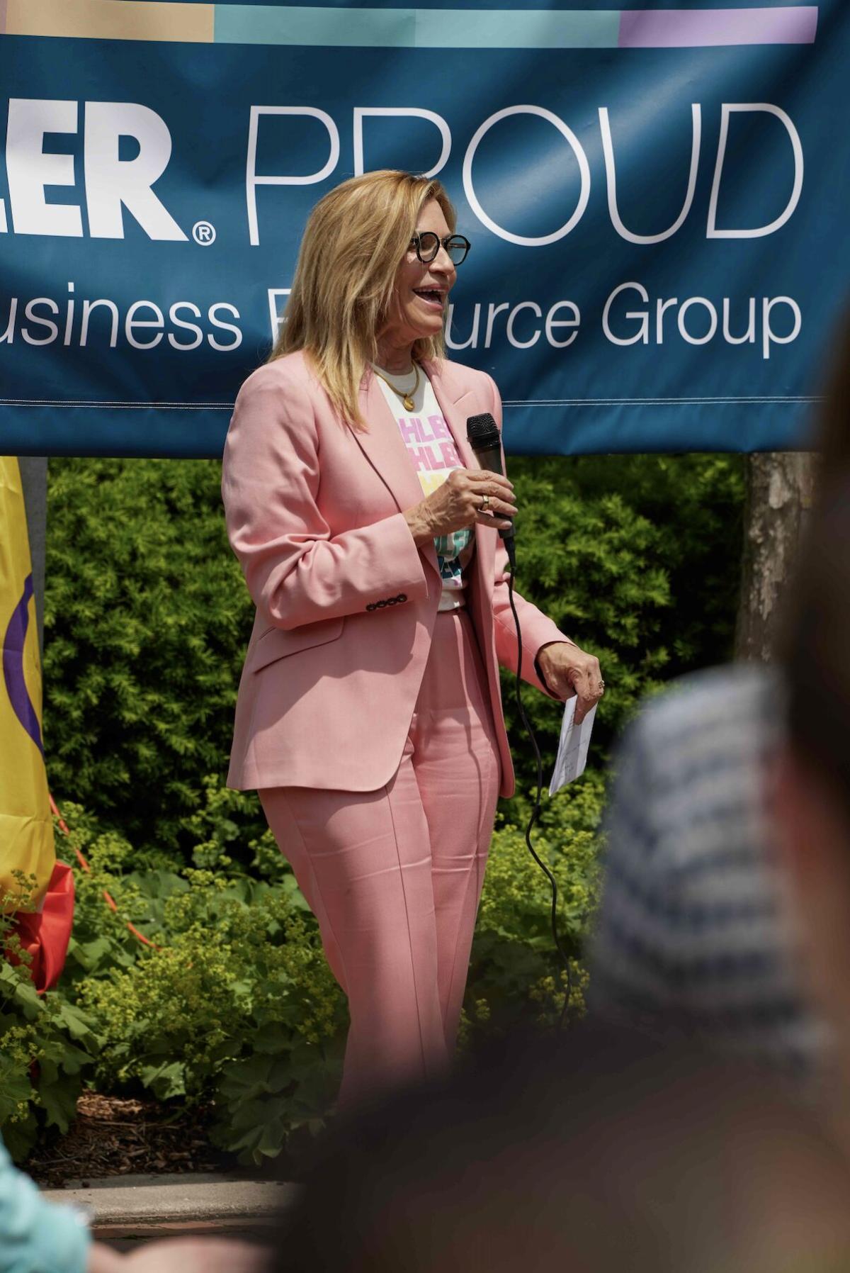 A person speaking to a group, a banner behind them "Kohler Proud".