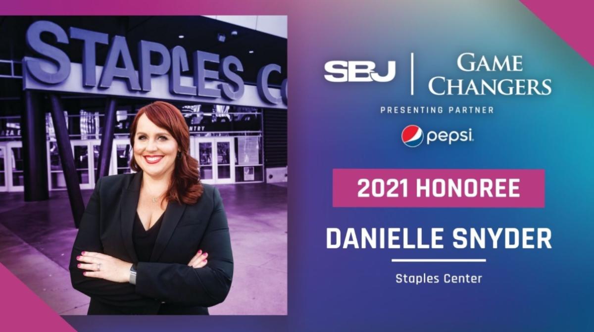 Danielle Snyder stands before the STAPLES Center sign and smiles. 