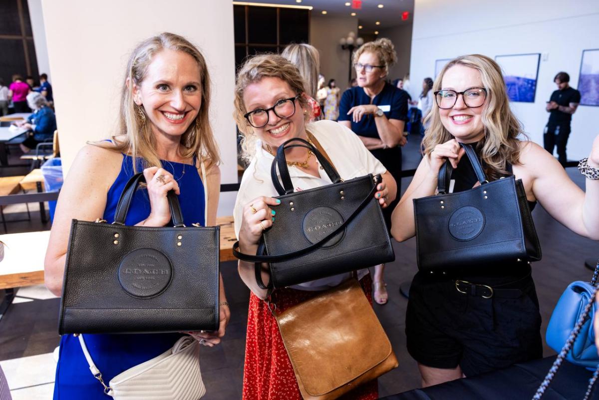 Three women holding black coach handbags