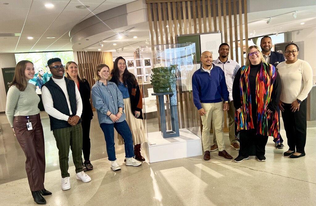 A group of people posed by a sculpture in a gallery.