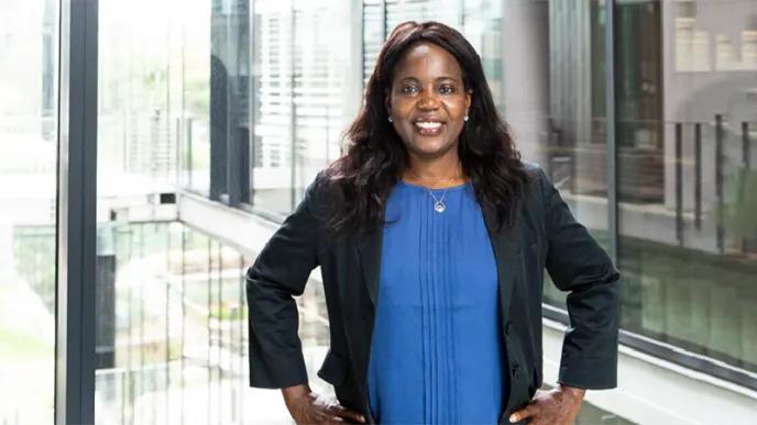 Dr. Lola Awoniyi-Oteri standing in front of a large window of an office building