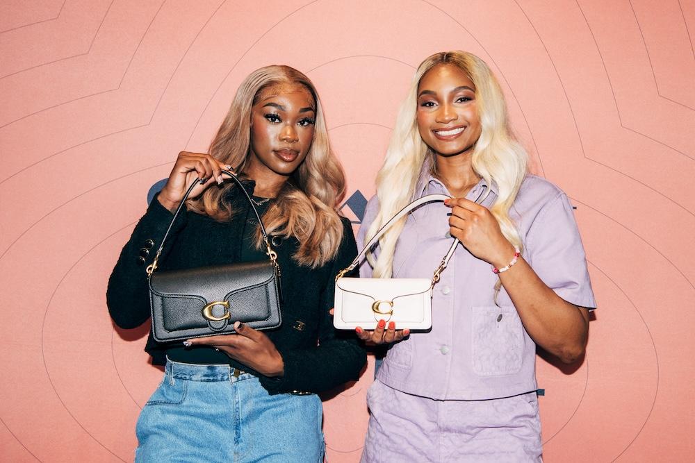 Two people holding up handbags