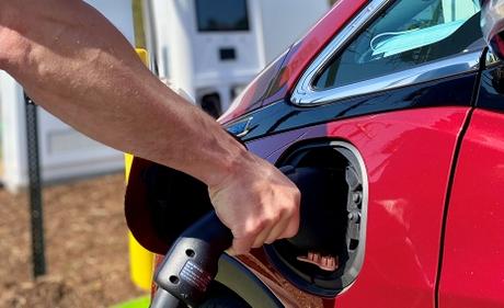 An arm holding a charger in an Electric Vehicle port.