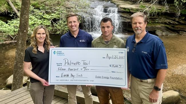 Four people holding up a check made out to Palmetto Trail for $5000