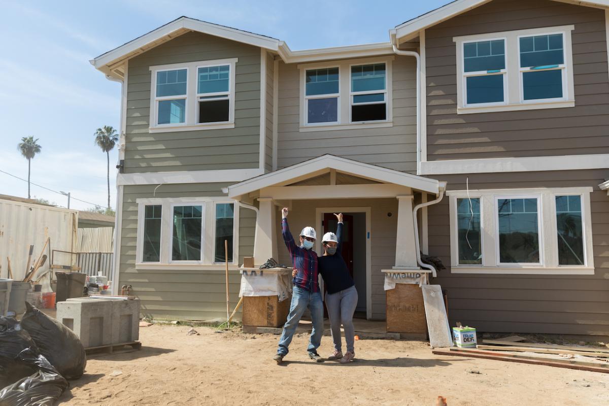 Cynthia E., her husband Valdemar C. pose outside of their new home by Habitat