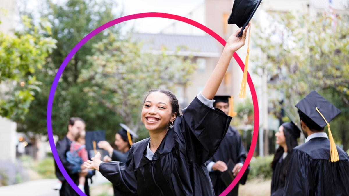 A student wearing a graduation gown, holding up their cap 