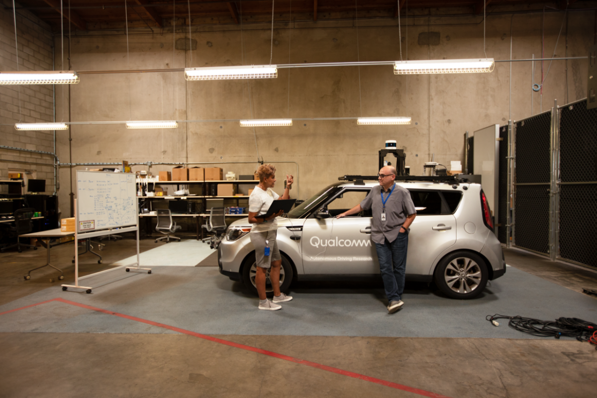 Engineers testing in auto lab in front of car