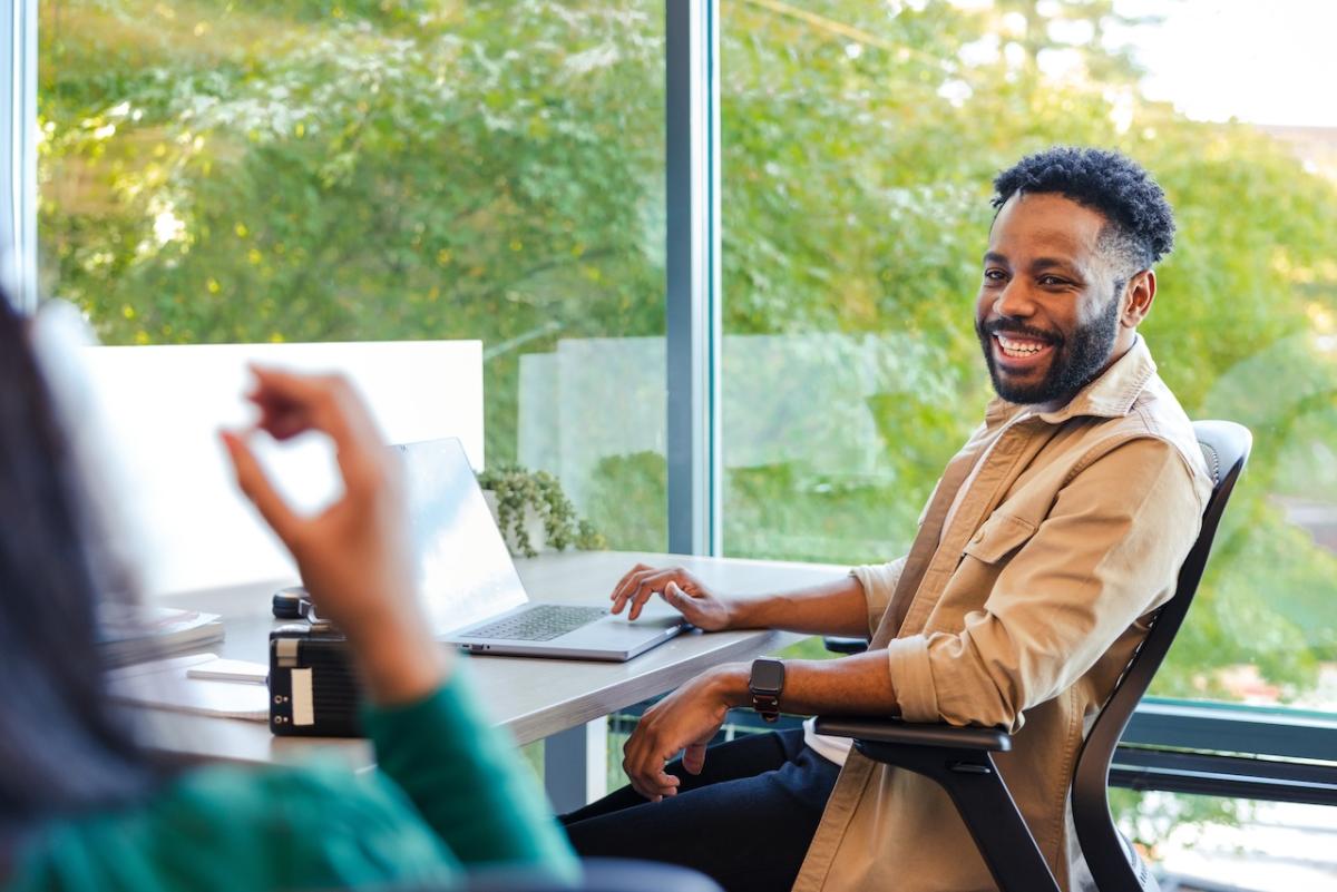 GoDaddy Team Member seated at a desk by a glass window.