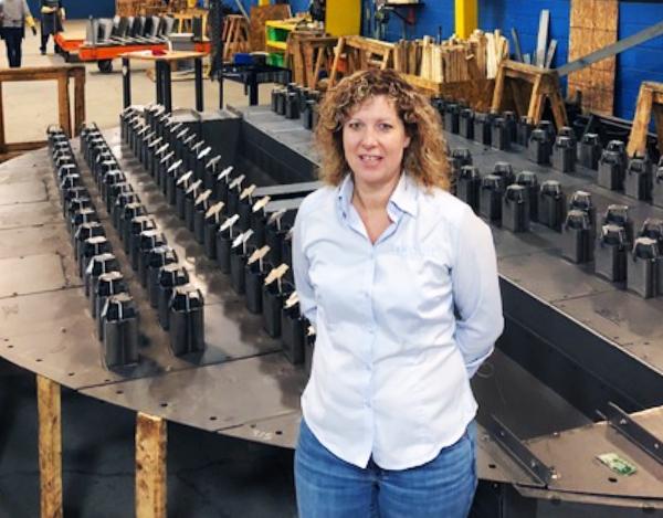 Esther Harper standing in front of neat rows of metal parts