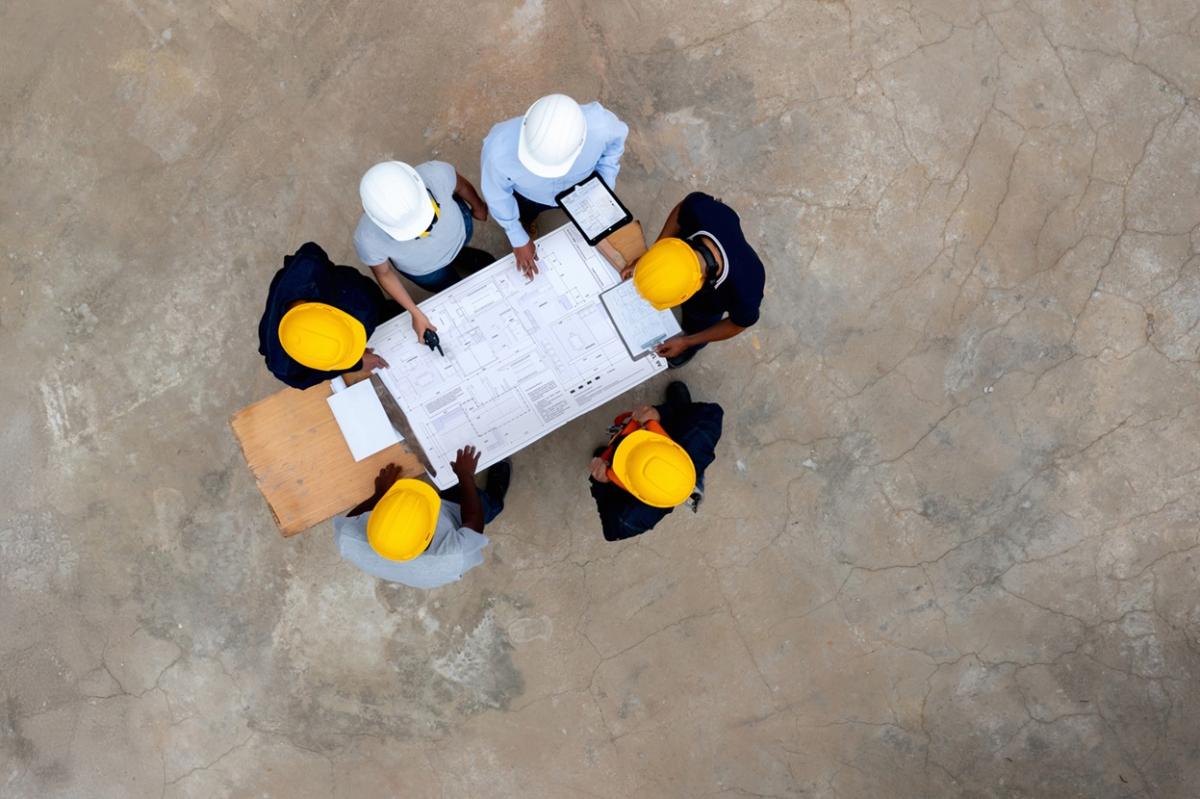 Aerial view of engineers around a table with a blueprint