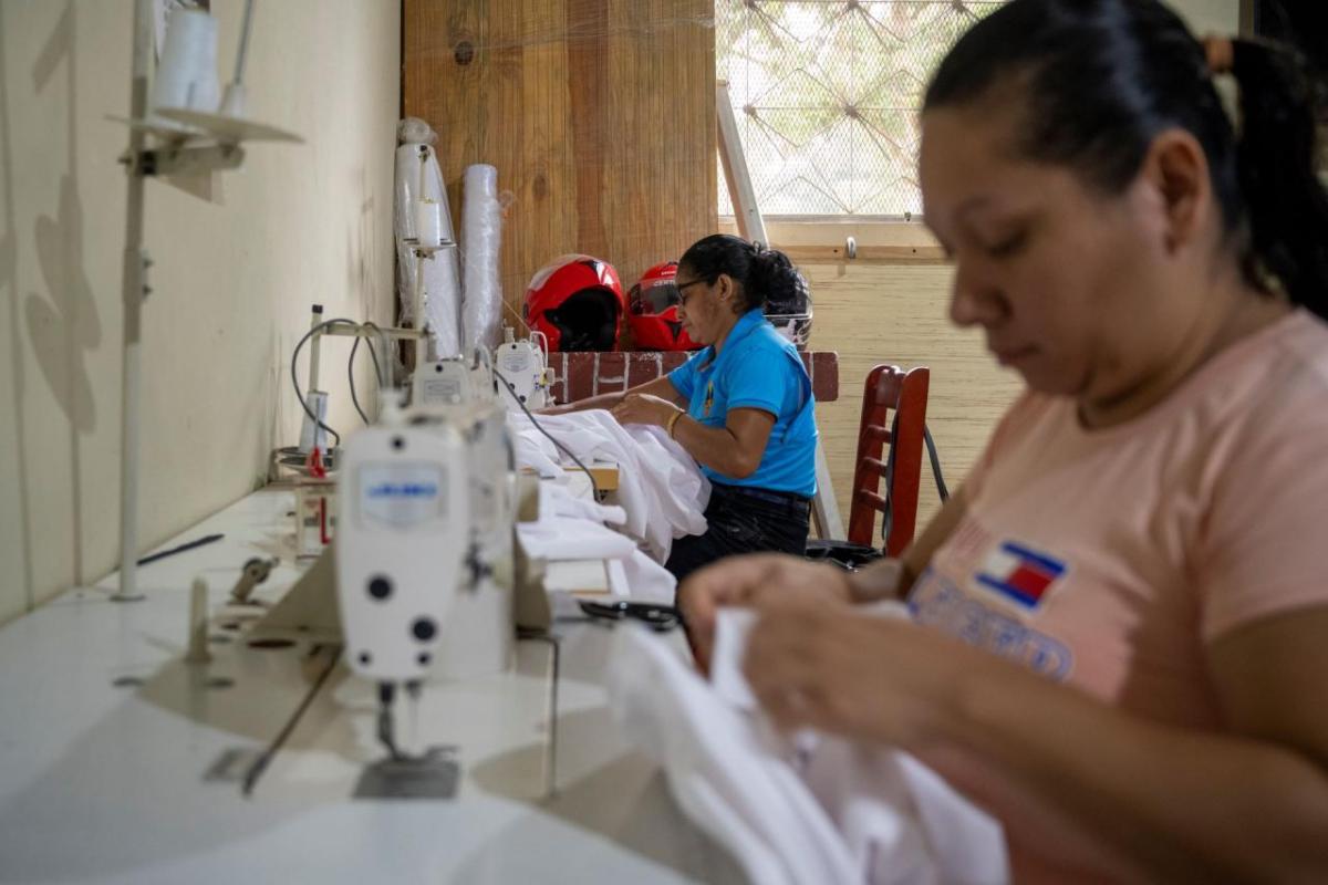 Women sew overalls for other cooperative members.