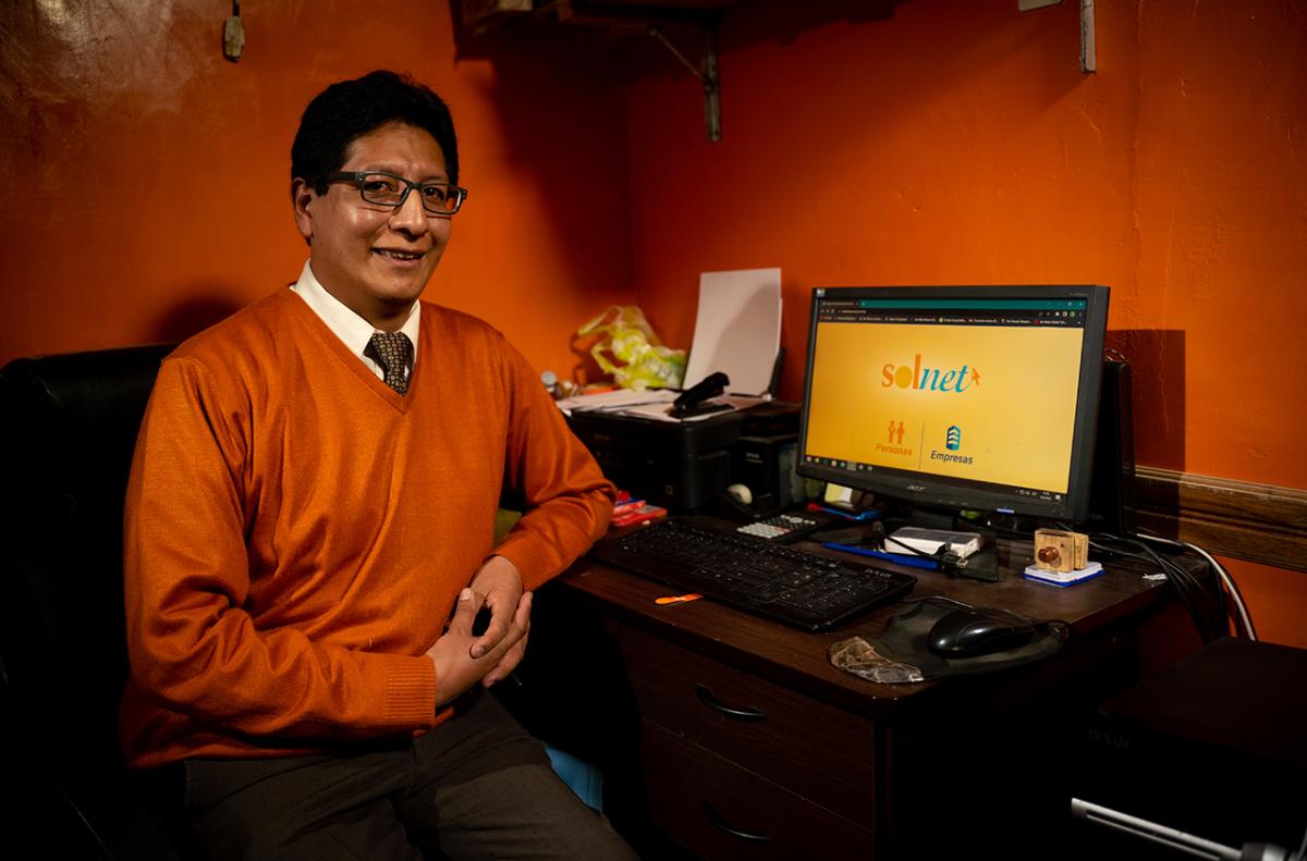 Fernando sitting at a desk with a laptop open to "Solnet."