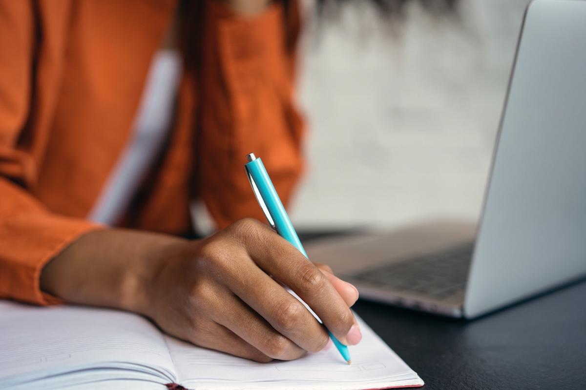 Person shown writing in a notebook.