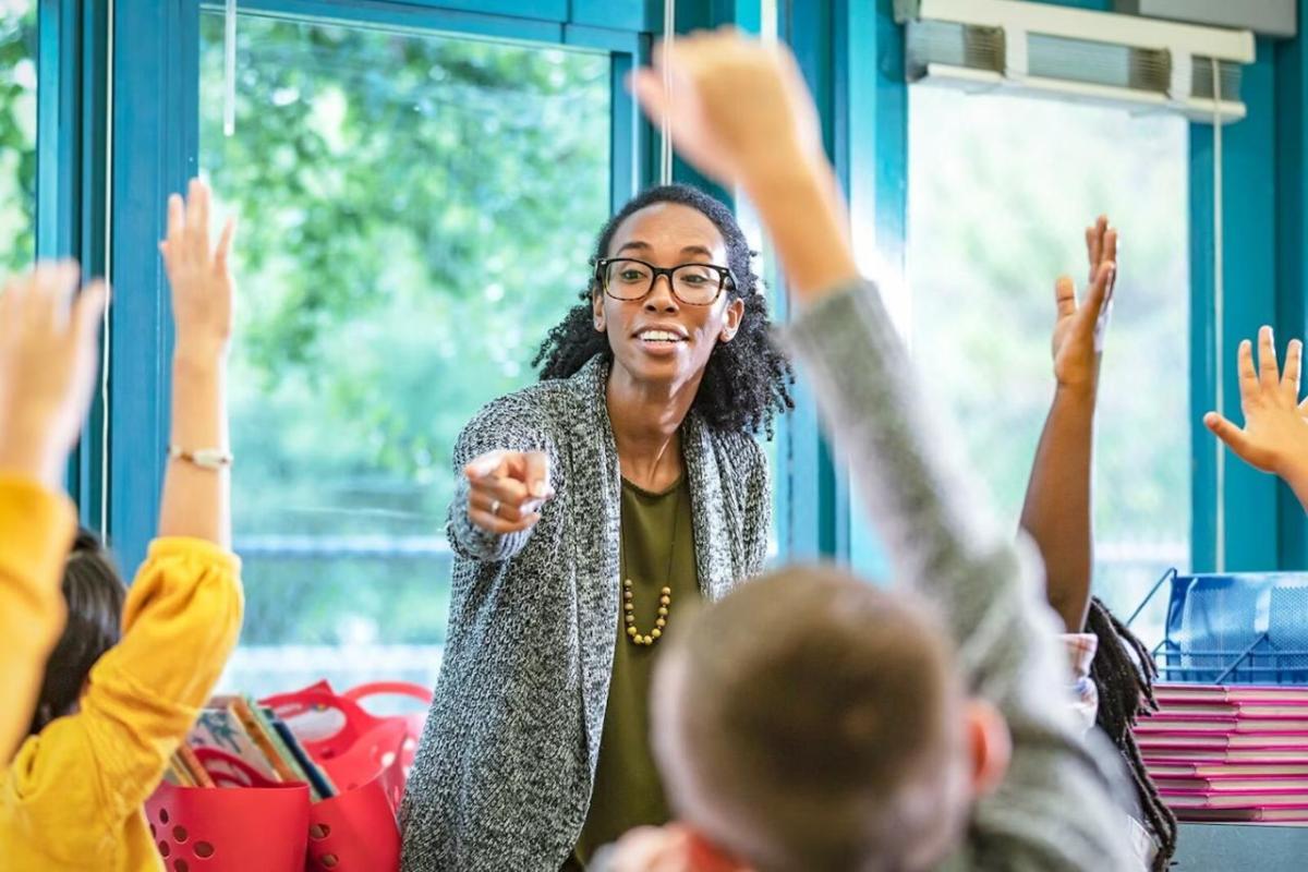 A teacher pointing to students with their hand raised 